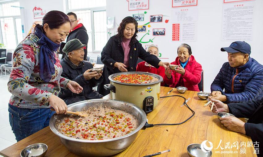 呼和浩特市玉泉區清泉街社區志願者為老人們端上熱氣騰騰的臘八粥。