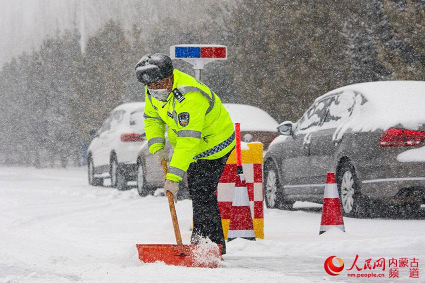 2月14日，阿魯科爾沁旗交通管理大隊民警在風雪中堅守防疫一線，維持交通秩序、進行道路清掃等工作，並對過往車輛及人員進行檢測、登記。張棖 張青林攝影報道