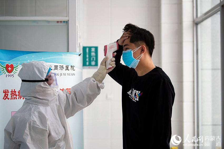 日前，在阿魯科爾沁旗同濟醫院的發熱門診，醫護人員為進入醫院的人員測量體溫。張棖 李忠慧攝影報道