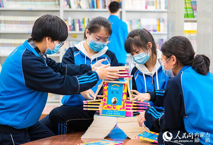呼和浩特市第二十六中學“小圖書管理員”在將書籍碼成漂亮的書堆造型。