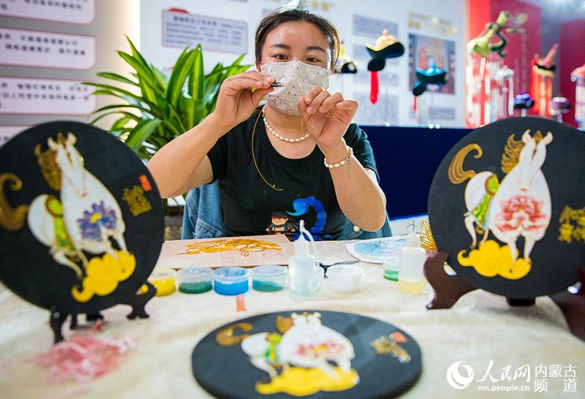 手工藝人在呼和浩特市玉泉區首屆女性手工藝品展上展示掐絲琺琅沙畫技藝。
