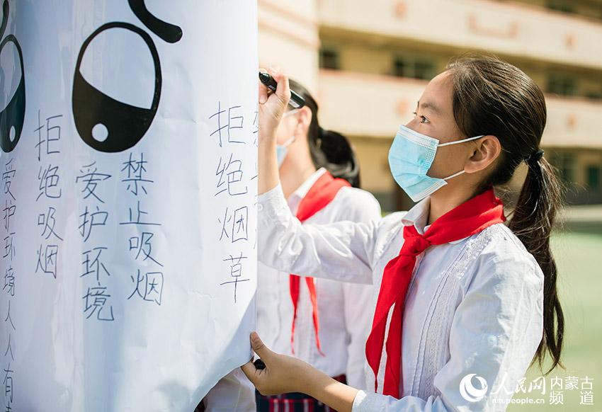 5月28日，內蒙古自治區呼和浩特市玉泉區恆昌店巷小學學生在自制的巨型“香煙”上簽名。