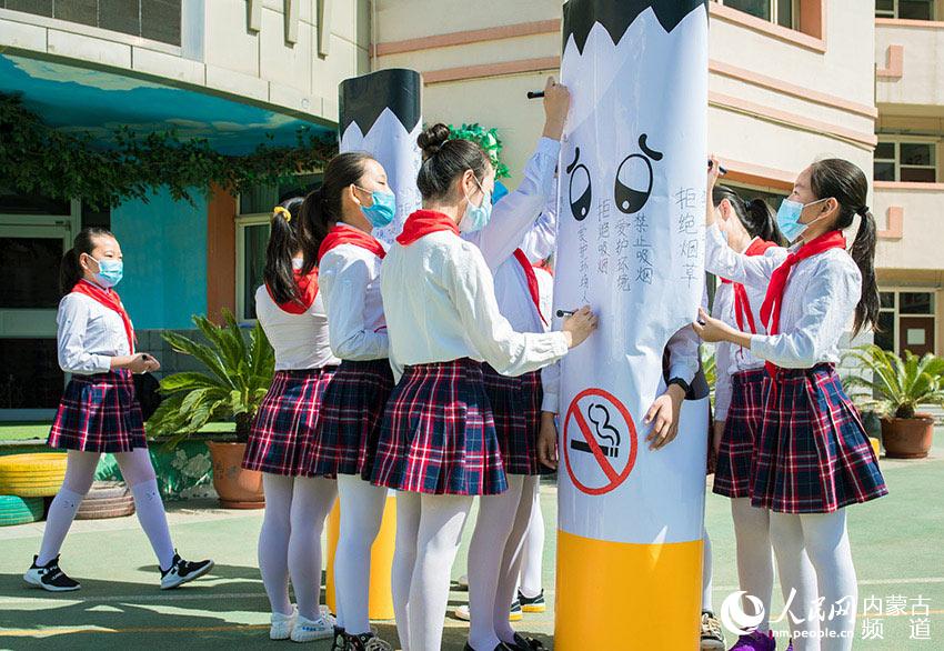 5月28日，內蒙古自治區呼和浩特市玉泉區恆昌店巷小學學生在自制的巨型“香煙”上簽名。
