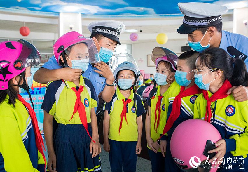 內蒙古呼和浩特市玉泉區通順街小學學生在交警的指導下學習正確佩戴安全頭盔。