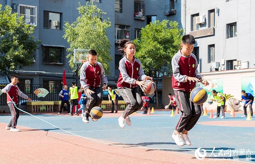 內蒙古呼和浩特市玉泉區石頭巷小學學生在戶外籃球特色體育課上進行趣味籃球訓練。