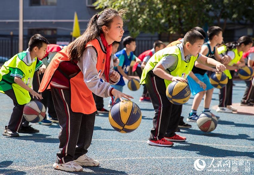 內蒙古呼和浩特市玉泉區石頭巷小學學生在戶外籃球特色體育課上進行籃球基礎技術訓練。