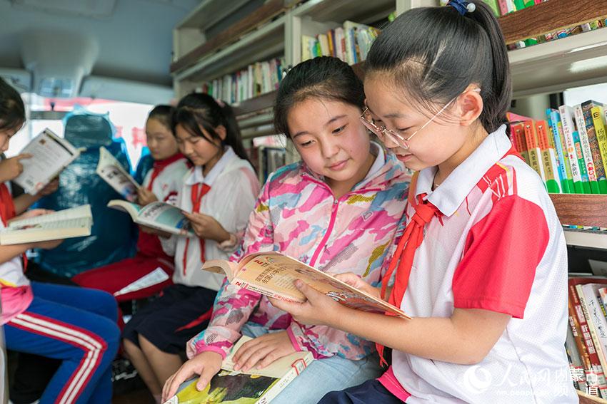 內蒙古呼和浩特市玉泉區恆昌店巷小學的孩子們在“流動圖書車”內翻閱圖書。