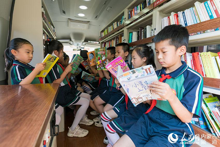內蒙古呼和浩特市玉泉區恆昌店巷小學的孩子們在“流動圖書車”內翻閱圖書。