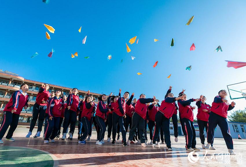 內蒙古自治區呼和浩特市第二十七中學初三學生將寫有自己夢想的紙飛機拋向空中。