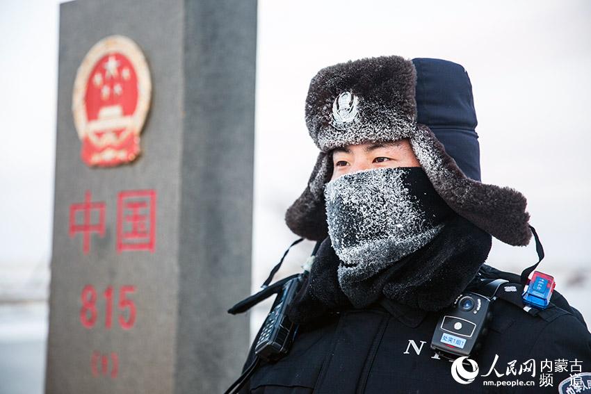 二連出入境邊防檢查站民警在中蒙邊境815號界碑前執勤，民警帽子和防寒面罩上挂滿冰霜。