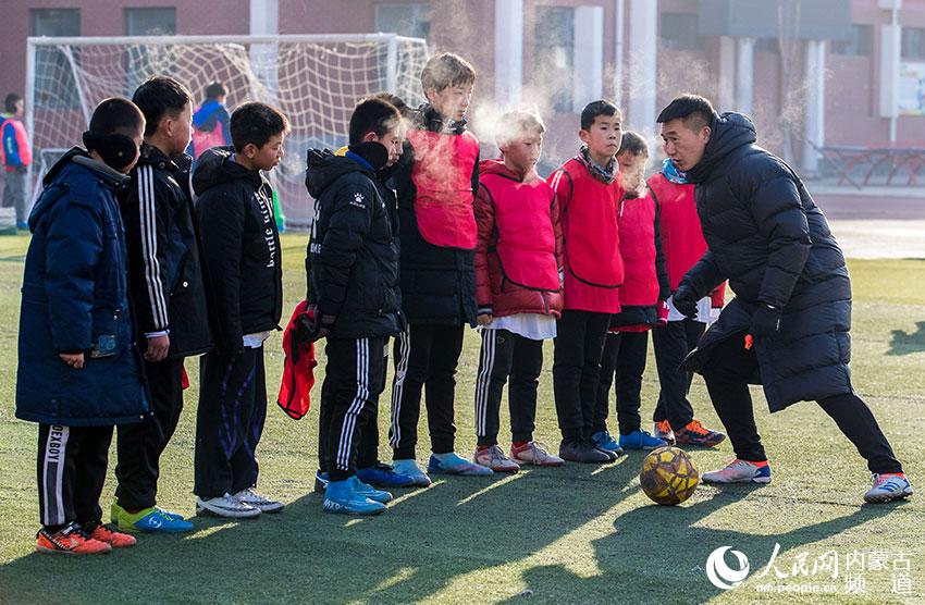 足球教練在呼和浩特市玉泉區恆昌店巷小學為小球員示范動作。