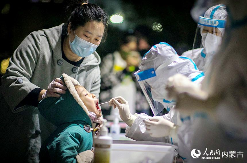 夜间，在呼和浩特市玉泉区恒泰盛都小区内的一个核酸检测点，医务人员对居民进行核酸检测取样。丁根厚摄