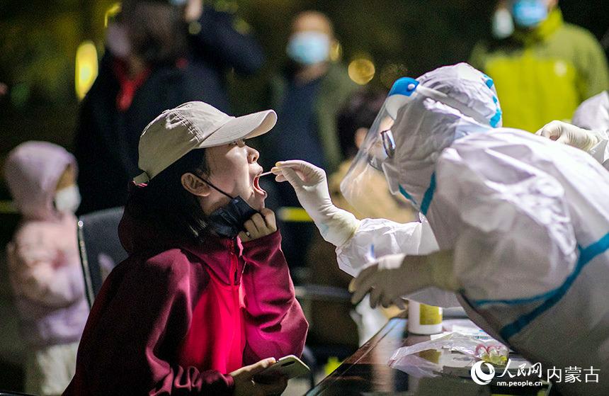 夜間，在呼和浩特市玉泉區恆泰盛都小區內的一個核酸檢測點，醫務人員對市民進行核酸檢測取樣。丁根厚攝