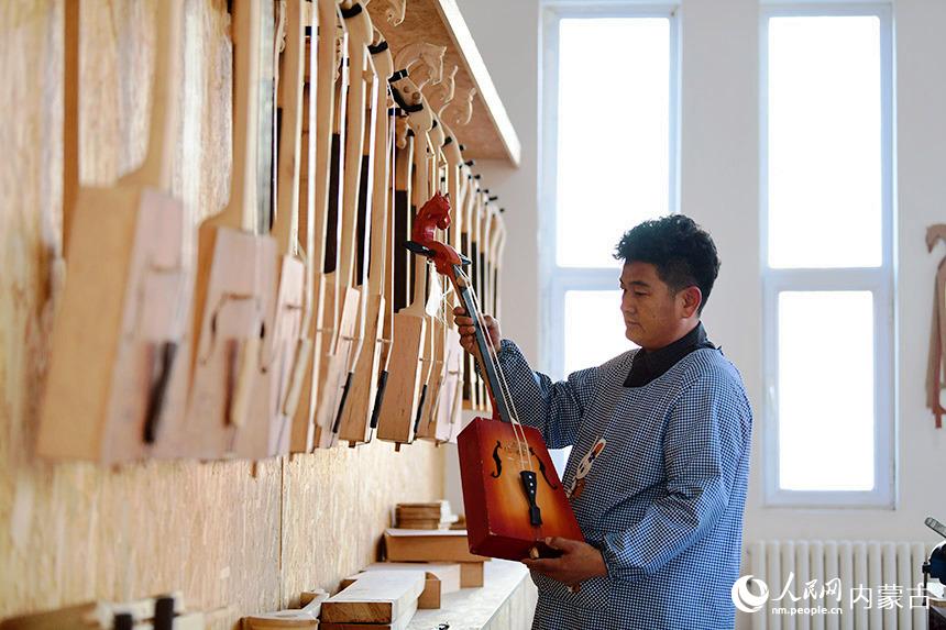 胡雅格正在選看學生制作的馬頭琴。人民網 劉藝琳攝