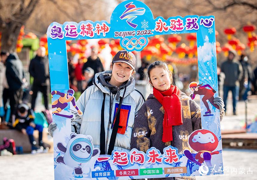 呼和浩特市玉泉區恆昌店巷小學學生和家長手持祝福北京冬奧會的字樣在青城公園公益冰雪場合影留念。丁根厚攝