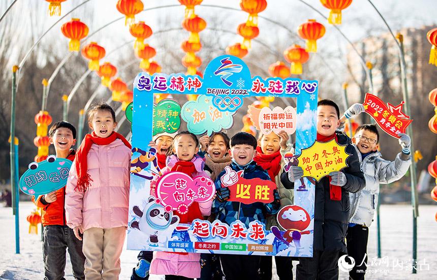 呼和浩特市玉泉區恆昌店巷小學學生手持祝福北京冬奧會的字樣在青城公園公益冰雪場合影留念。丁根厚攝