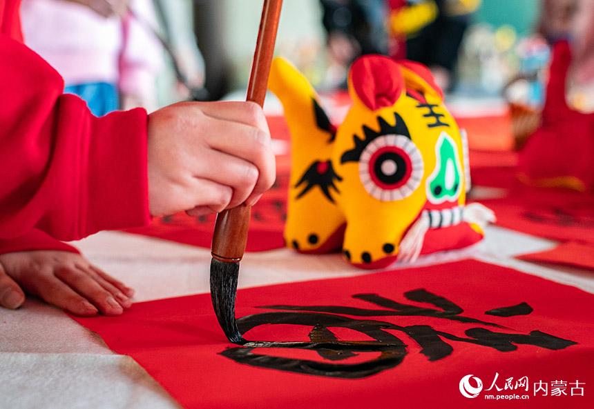 呼和浩特市玉泉區恆昌店巷小學書法社團師生在書寫“福”字和春聯。丁根厚攝