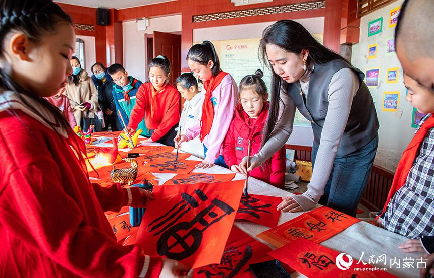 呼和浩特市玉泉區恆昌店巷小學書法社團師生在書寫“福”字和春聯。丁根厚攝