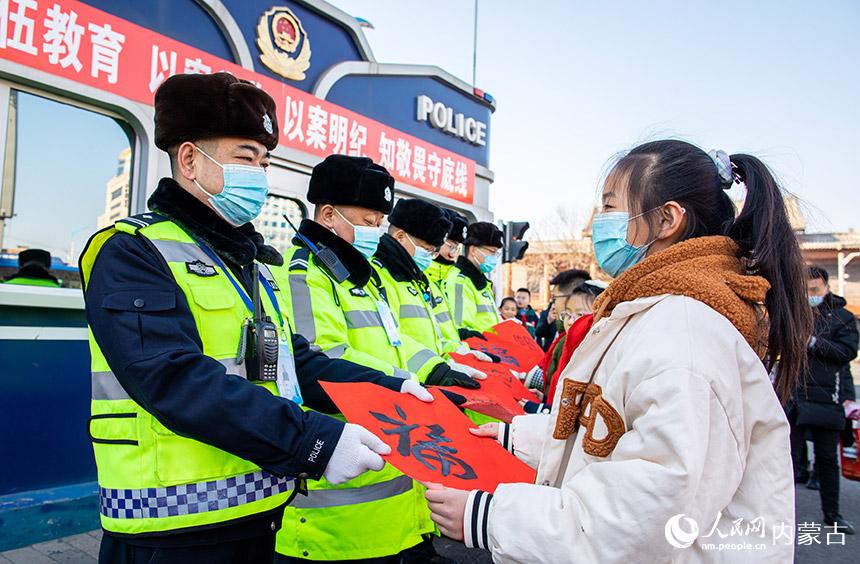 呼和浩特市玉泉區恆昌店巷小學“小書法家”為交警送上自己書寫的“福”字和春聯。丁根厚攝