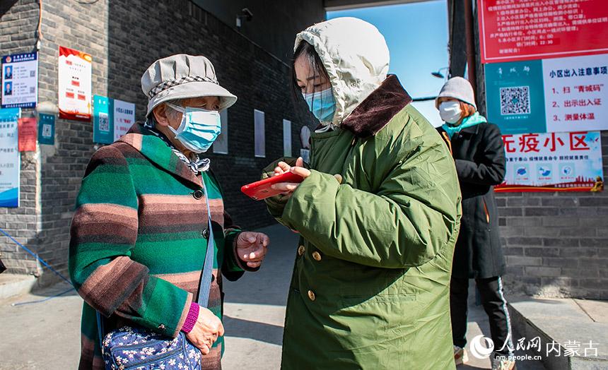 工作人員在呼和浩特市玉泉區大南街街道梁山街社區泉盛小區出入口幫助老年人注冊“青城碼”。丁根厚攝