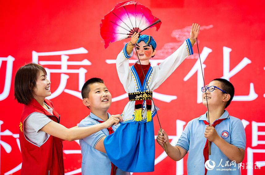 呼和浩特市玉泉區文化館的黨員志願者為學生們講解杖頭木偶的表演技藝。丁根厚攝