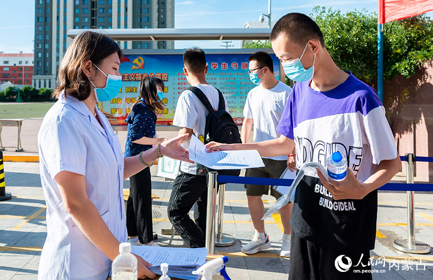 在呼和浩特市第二十六中學考點，工作人員（左）查驗考生健康情況承諾書。丁根厚攝