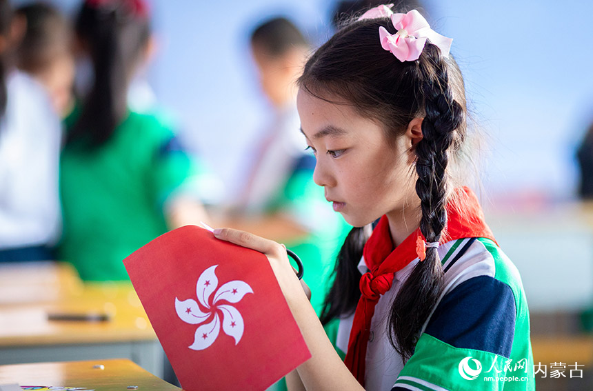 呼和浩特市玉泉區石頭巷小學學生在制作以“慶祝香港回歸祖國25周年”為主題的剪紙作品。丁根厚攝