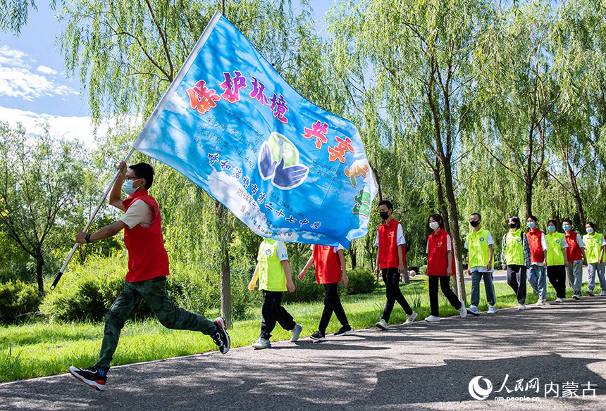 呼和浩特市第二十七中学的学生志愿者以手持彩旗巡游的方式向市民宣传保护环境，爱护城市卫生。丁根厚摄