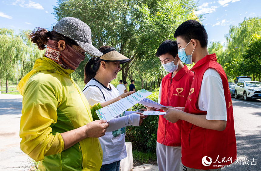 呼和浩特市第二十七中学的学生志愿者在南湖湿地公园内向市民宣传创城知识,发放市民文明手册。丁根厚摄