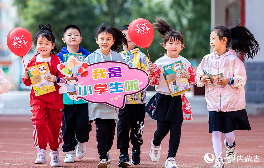 呼和浩特市玉泉区南柴火市街小学的一年级新生们手持新教材，开心的奔跑在校园内。丁根厚摄