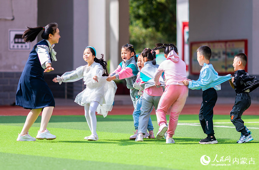 呼和浩特市玉泉区南柴火市街小学老师和一年级新生在操场上玩游戏。丁根厚摄