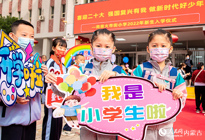 呼和浩特市玉泉区南柴火市街小学双胞胎一年级新生手持“我是小学生啦”牌子在校园内留影。丁根厚摄