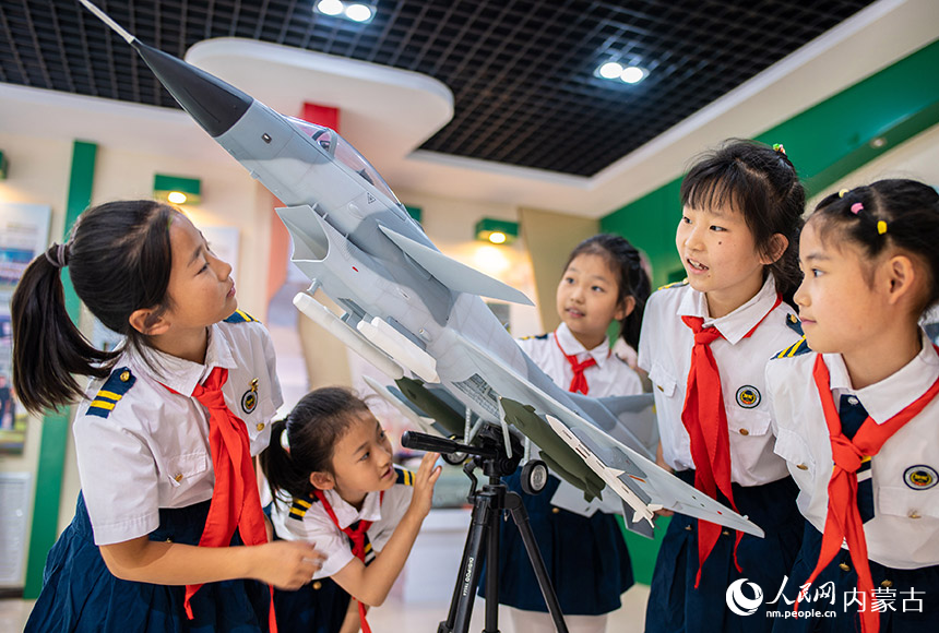 呼和浩特市玉泉区五塔寺东街小学少年军校学生在学校国防教育展厅观看军事装备模型。丁根厚摄