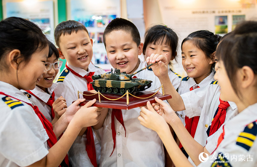 呼和浩特市玉泉区五塔寺东街小学少年军校学生在学校国防教育展厅观看军事装备模型。丁根厚摄