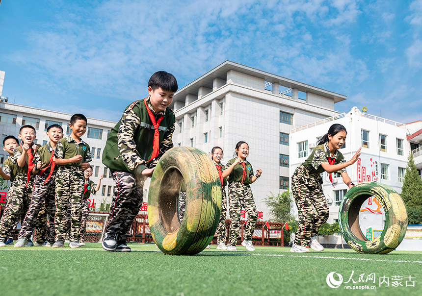 呼和浩特市玉泉区五塔寺东街小学少年学生在进行趣味滚轮胎接力赛。丁根厚摄