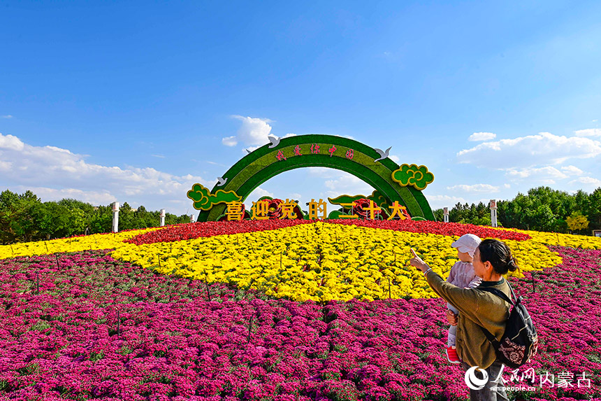 游客在鄂尔多斯市康巴什区“祝福祖国 喜迎二十大”主题花坛前游览。王正摄