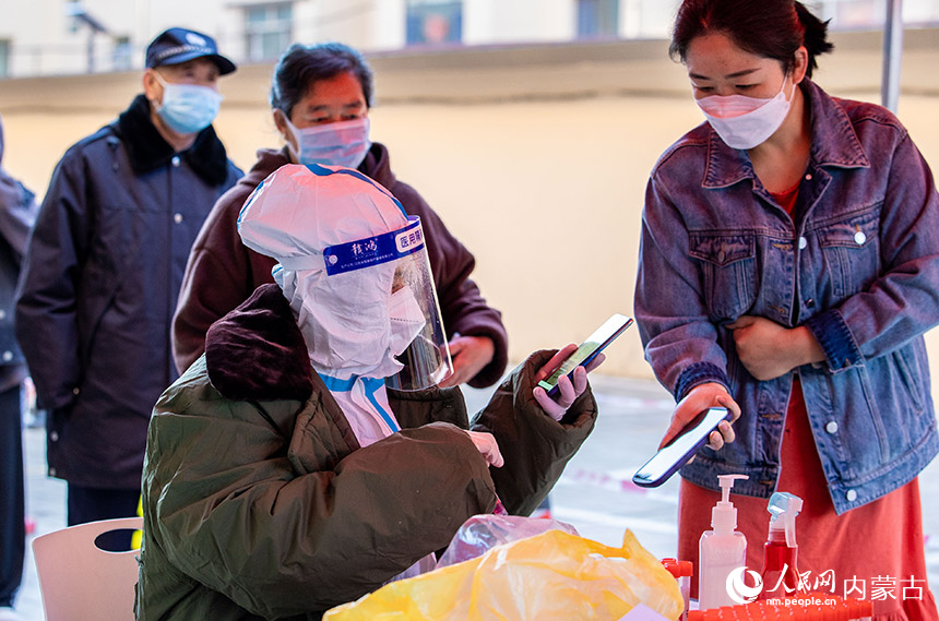 呼和浩特市玉泉區一處核酸篩查點，志願者在登記核酸受檢人員信息。丁根厚攝