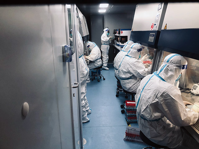 核酸檢測工作人員在狹小密閉的負壓實驗室裡開展檢測工作。
