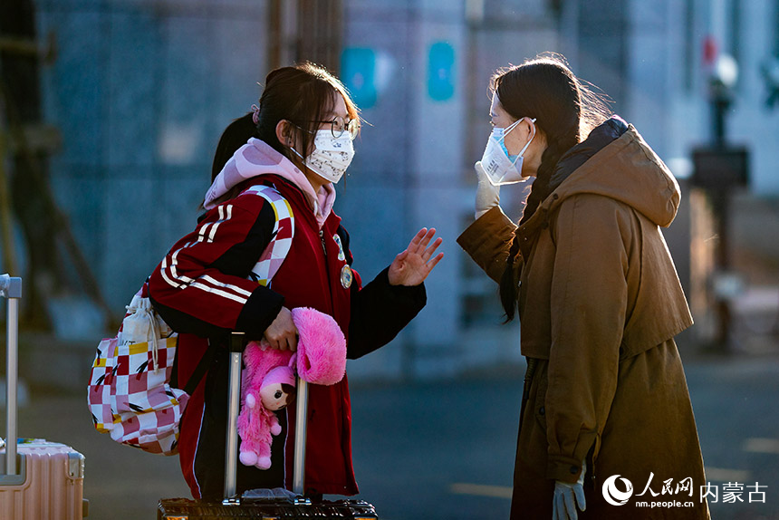 12月15日，呼和浩特市第十二中學返校復課的高三年級學生進入學校時向老師招手示意。丁根厚攝