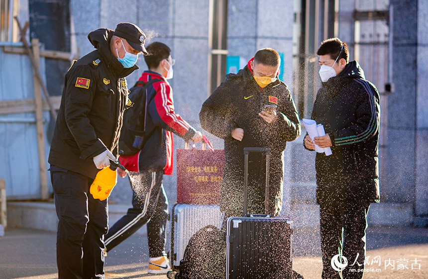 12月15日，呼和浩特市第十二中学工作人员在校门口为返校学生的行李进行消杀。丁根厚摄