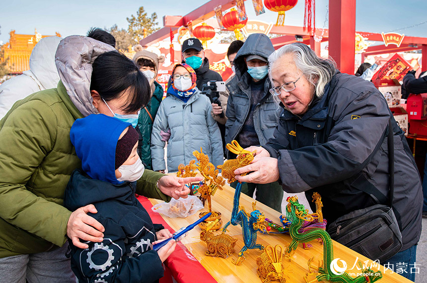 顾客在塞上老街年货节上选购非遗金属丝编工艺品。丁根厚摄
