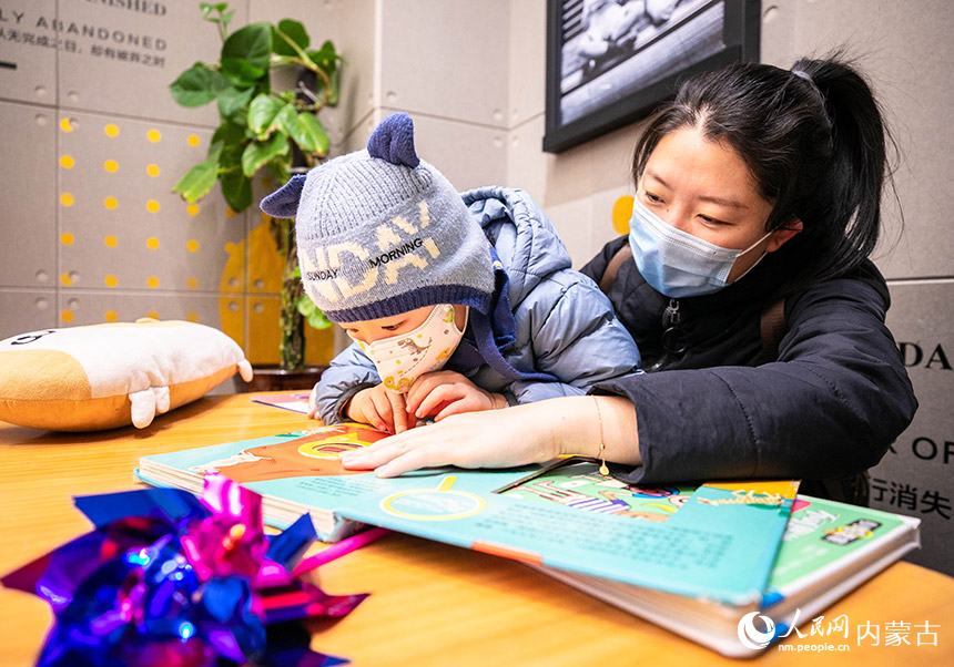 一名家长陪伴孩子在位于呼和浩特市玉泉区的西西弗书店（凯德店）阅览儿童读物。丁根厚摄