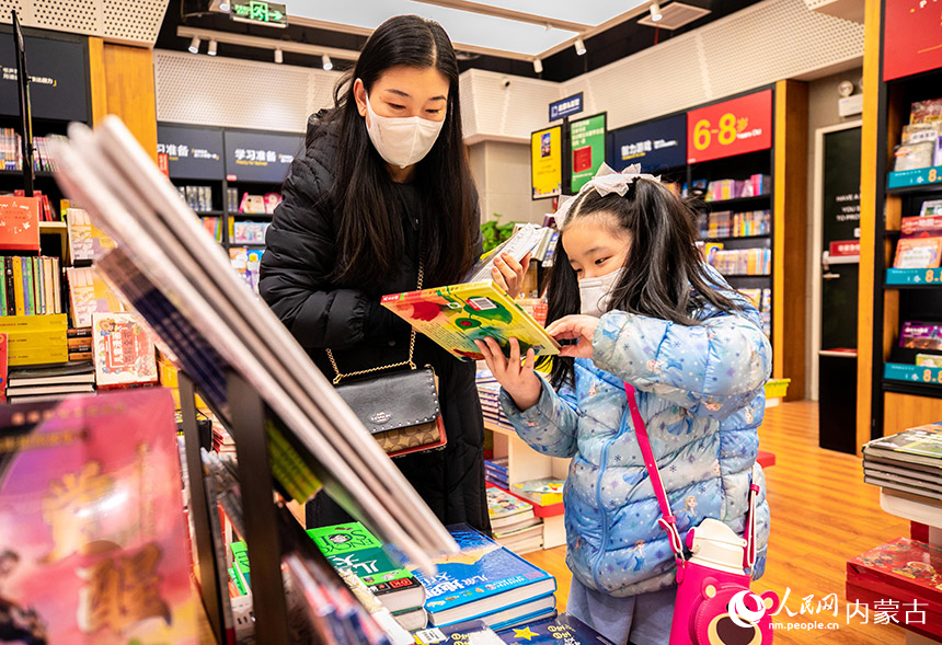 一名家长陪伴孩子在位于呼和浩特市玉泉区的西西弗书店（凯德店）挑选图书。丁根厚摄