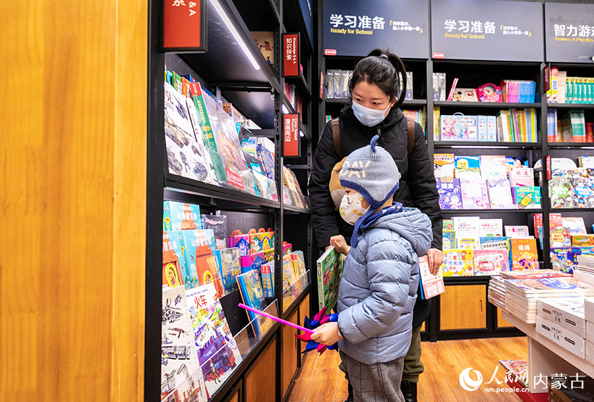 一名家长陪伴孩子在位于呼和浩特市玉泉区的西西弗书店（凯德店）挑选图书。丁根厚摄
