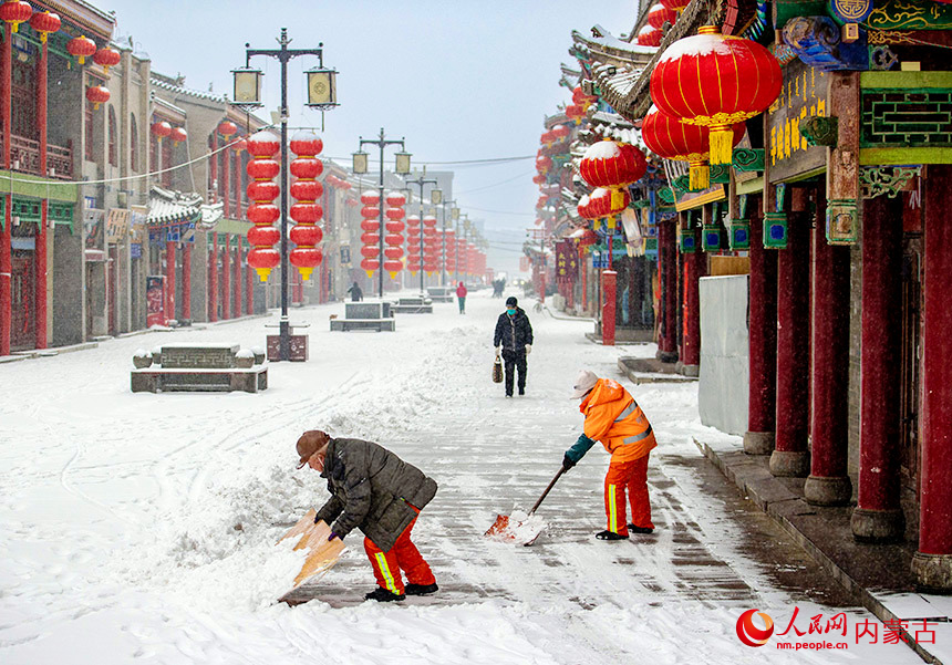 2月9日，呼和浩特市玉泉环境卫生服务中心的环卫工人在塞上老街历史文化街区清扫积雪。丁根厚摄