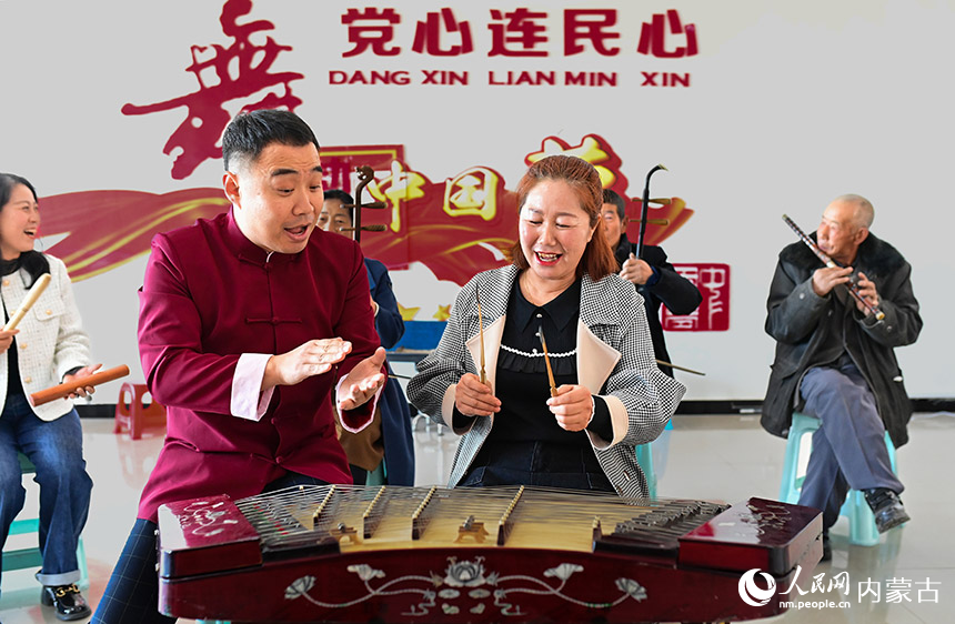 3月3日，在二连浩特市格日勒敖都苏木赛乌素嘎查文化室，文艺志愿者赵伟刚（左）为洋琴音乐爱好者指导演奏技艺。王正摄