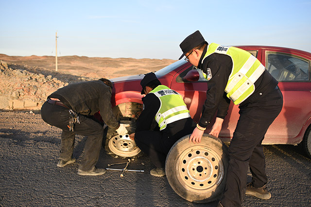 民警帮助被困车辆更换轮胎。肖鹏摄
