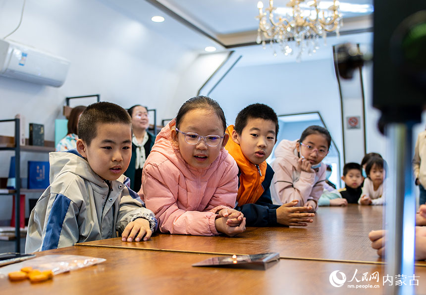 孩子们在位于内蒙古呼和浩特市玉泉区的神凫琥珀展馆内观看琥珀燃烧原理实验秀。丁根厚摄