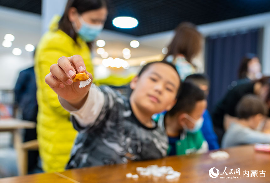 孩子们在位于内蒙古呼和浩特市玉泉区的神凫琥珀展馆内进行琥珀摩擦起电原理小实验。丁根厚摄
