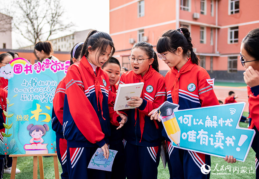 4月17日，内蒙古呼和浩特市玉泉区南茶坊小学学生在“图书漂流”集市上向伙伴介绍自己准备交换的图书。丁根厚摄